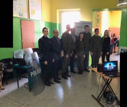 Dyrektor szkoły w Kościelcu wraz z policjantką i młodzieżą ubraną w mundury pozują do zdjęcia.