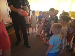 Policjant pokazuje dzieciom przedmioty mogące pomóc w uratowaniu osoby tonącej
