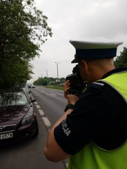 policjant namierzający miernikiem prędkości jadące pojazdy