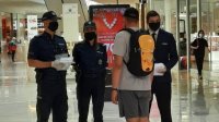 policjanci, którzy sprawdzają czy osoby noszą maseczki ochronne w centrum handlowym