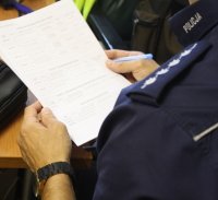 policjant trzymający w ręku dokumenty