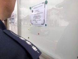 policjant przypinający ulotkę na tablicy informacyjnej